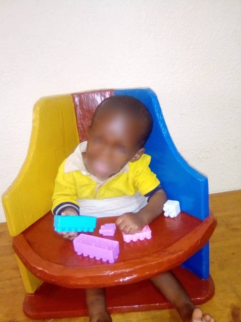 A boy writing at his school desk, seated in a supportive chair alongside his classmates