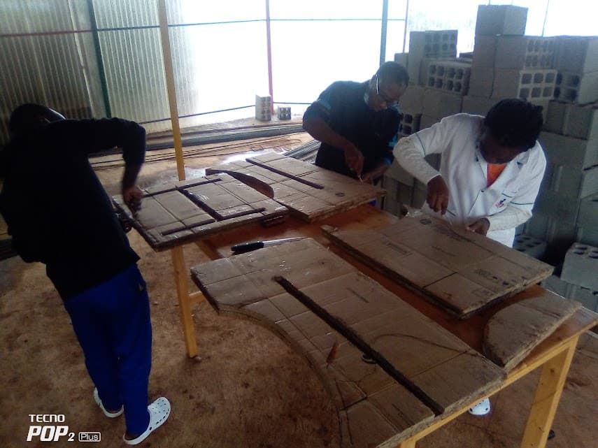 Three members of the workshop team assembling wooden panels for chair trays on a workbench
